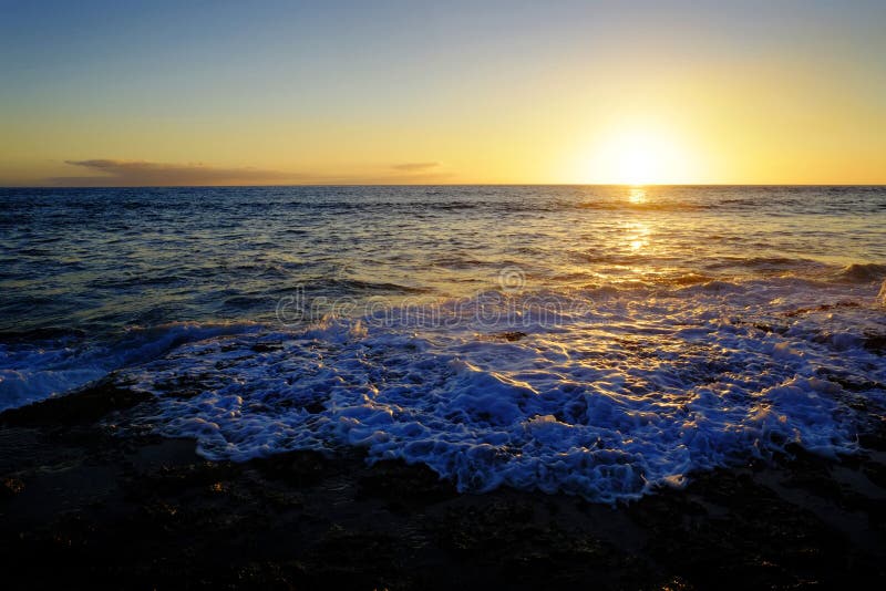 A onda de água do oceano que lava acima na praia balança a luz do sol do por do sol fotos de stock A onda de água do oceano que lava acima na praia balança a luz do sol do por do sol fotos de stock