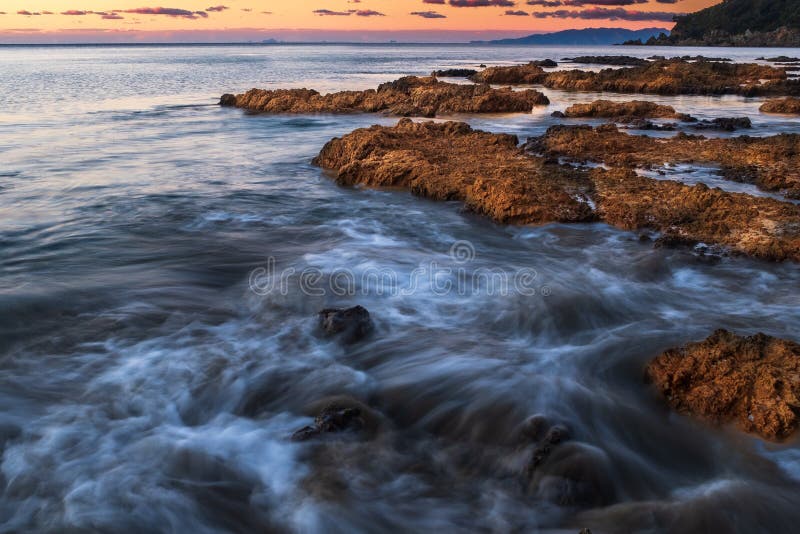 Onde che si schiantano sopra le rocce sulla linea costiera dentellata dell'isola di Waiheke, Nuova Zelanda presa su un'esposizion fotografia stock Onde che si schiantano sopra le rocce sulla linea costiera dentellata dell'isola di Waiheke, Nuova Zelanda presa su un'esposizion fotografia stock