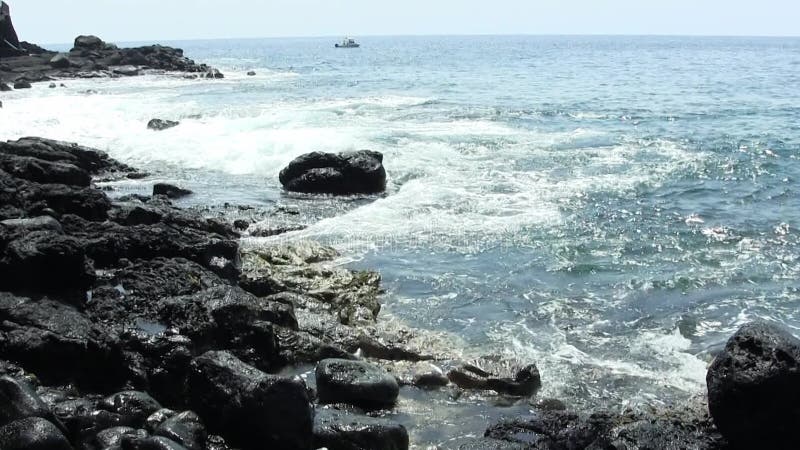 Onde oceaniche di hawaii riprese a mano che risalgono alla lava nera