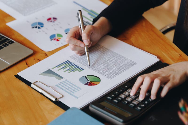 Onderneemster die aan calculator werken om bedrijfsgegevensfinancieel verslag op houten lijst te berekenen royalty-vrije stock afbeeldingen Onderneemster die aan calculator werken om bedrijfsgegevensfinancieel verslag op houten lijst te berekenen royalty-vrije stock afbeeldingen