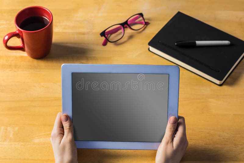Businesswoman using tablet at desk with coffee cup and diary. Businesswoman using tablet at desk with coffee cup and diary