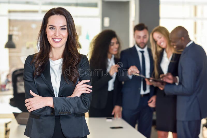 Onderneemsterleider in modern bureau met zakenlui die bij achtergrond werken