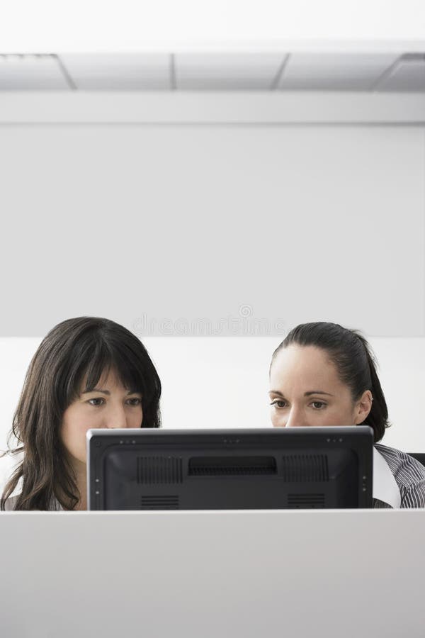 Onderneemsters die Computer in Cel met behulp van royalty-vrije stock foto Onderneemsters die Computer in Cel met behulp van royalty-vrije stock foto
