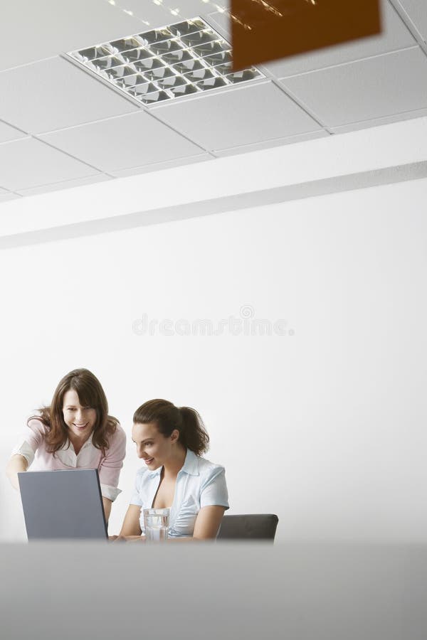 Onderneemsters die over Laptop op Vergadering in Bureau bespreken royalty-vrije stock foto Onderneemsters die over Laptop op Vergadering in Bureau bespreken royalty-vrije stock foto