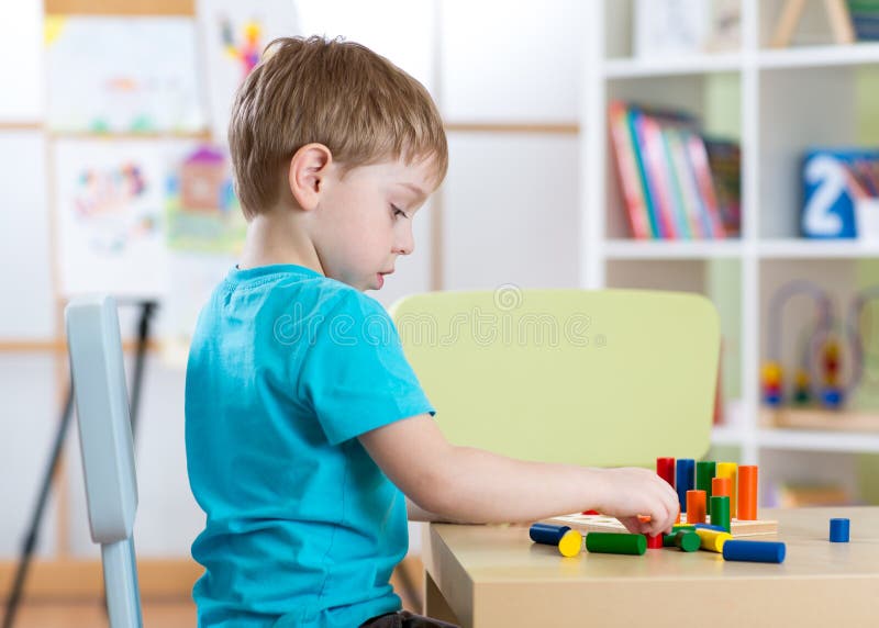 Onderwijsbeeld van kleuterschool Kindjongen het spelen met speelgoed bij lijst stock afbeeldingen Onderwijsbeeld van kleuterschool Kindjongen het spelen met speelgoed bij lijst stock afbeeldingen