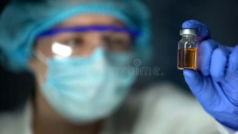 Onderzoeker die transparante bruinachtige vloeistof in fles, tegengifontwikkeling analyseren stock foto Onderzoeker die transparante bruinachtige vloeistof in fles, tegengifontwikkeling analyseren stock foto