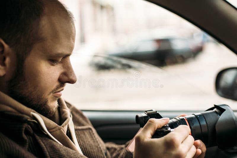 Onderzoeker of privé-detective of verslaggevers of paparazzizitting in auto en het nemen van foto met professionele camera stock afbeelding Onderzoeker of privé-detective of verslaggevers of paparazzizitting in auto en het nemen van foto met professionele camera stock afbeelding