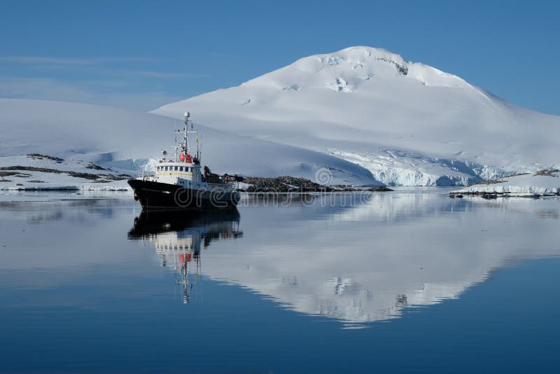 Ondinhas do barco da Antártica em uma baía azul do espelho abaixo neve branca da montanha tampada foto de stock Ondinhas do barco da Antártica em uma baía azul do espelho abaixo neve branca da montanha tampada foto de stock
