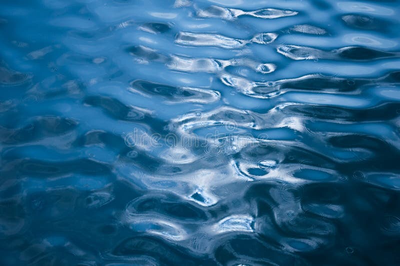 Water ripples with rain drops in a calm lake of Neuchatel with reflections of light. Water ripples with rain drops in a calm lake of Neuchatel with reflections of light