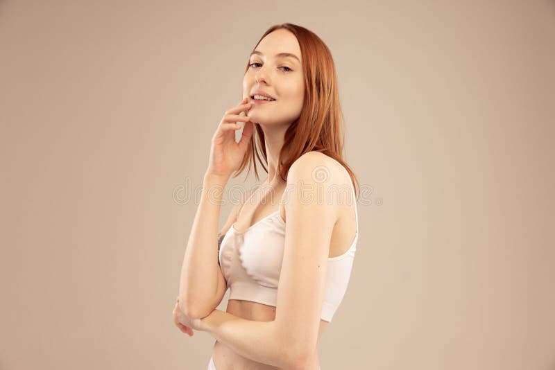 Young pretty woman with perfect slim body. Beautiful model wearing inner  wear, smiling and posing on grey background. Concept of beauty, body and  skin care, health, plastic surgery, cosmetics, ad Stock Photo