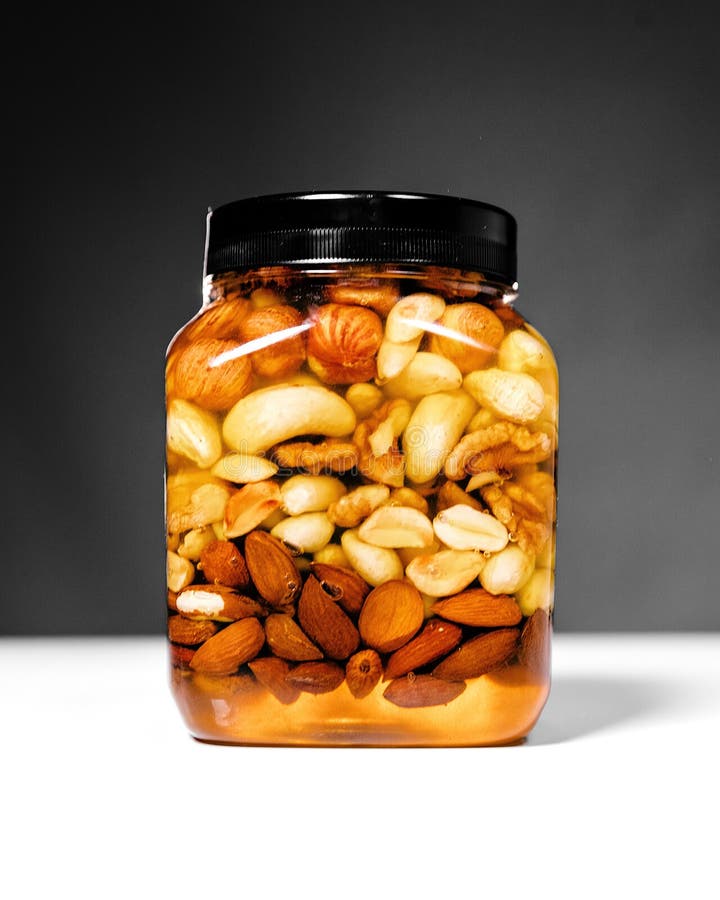 Premium Photo  Honey with various types of nuts in glass jars on a blue  background.