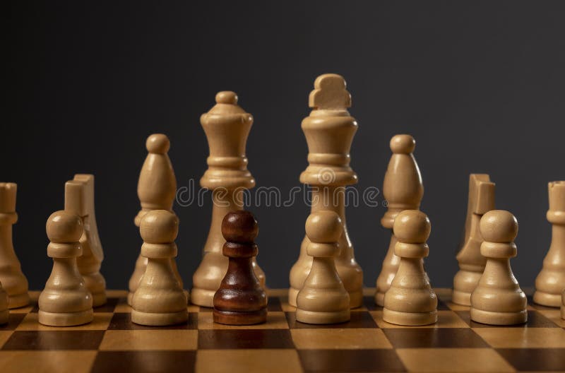 One black pawn unique and different in group of other chess pieces. Concept of diversity and uniqueness royalty free stock photography