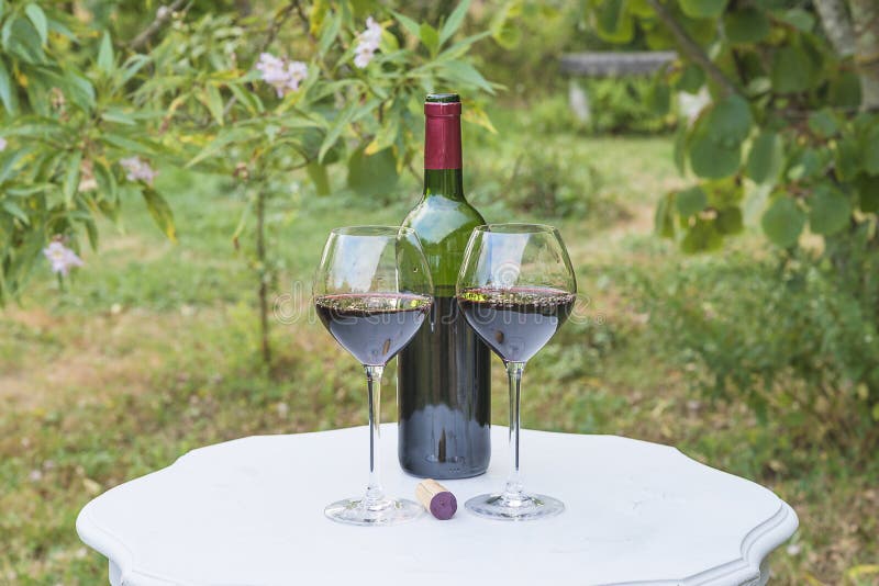 One bottle and two glasses of red wine on white vintage table