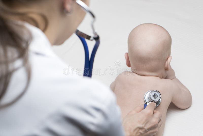 One caucasian female doctor is listening heartbeat of infant boy by stethoscope