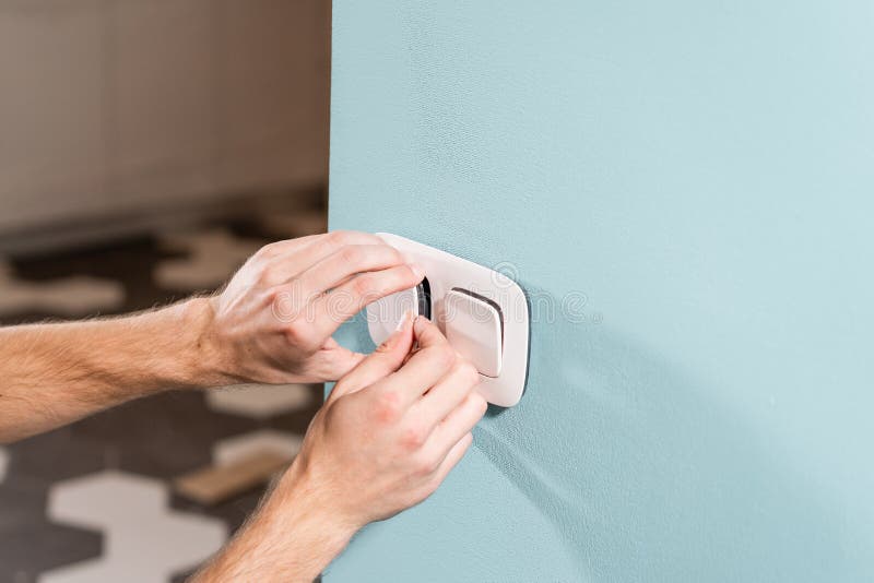 Electrician Worker Installs Light Switch and Socket on Wall in Room