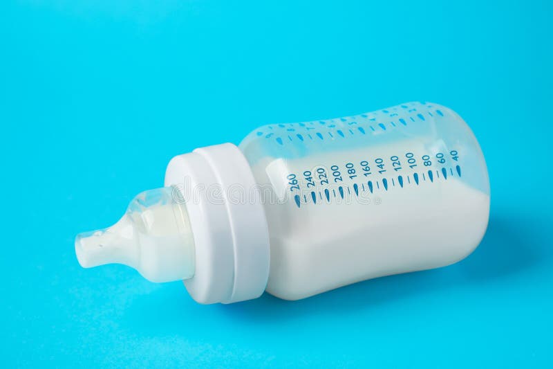 One Feeding Bottle with Milk on Light Blue Background, Closeup Stock