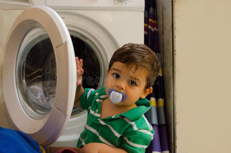 One and the Half Years Old Baby Boy Putting Clothes in Washing Machine