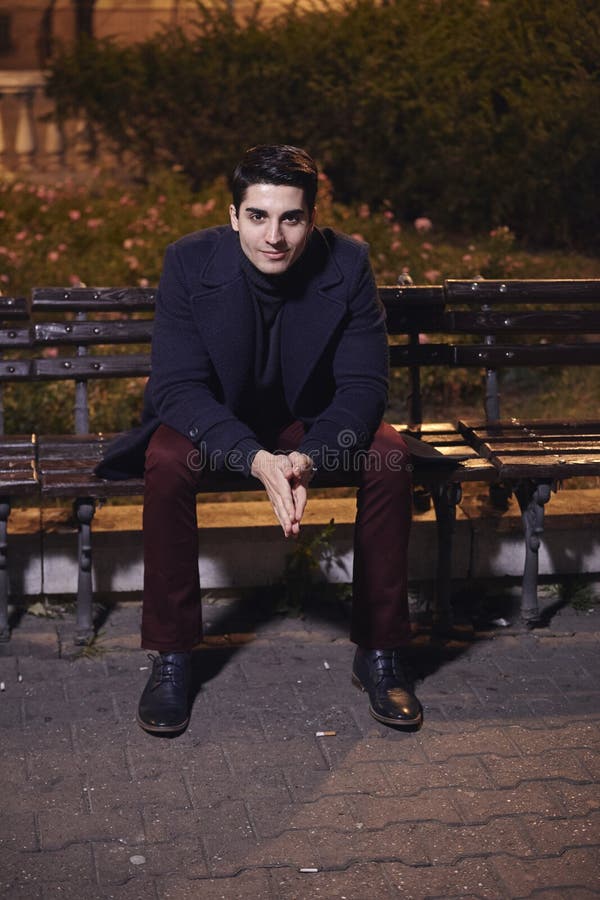 One handsome young man, 20-29 years old, posing, autumn clothes, sitting bench on city square. night time, dark royalty free stock image One handsome young man, 20-29 years old, posing, autumn clothes, sitting bench on city square. night time, dark royalty free stock image