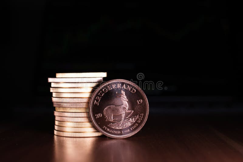 One Krugerrand Gold Coin Stands in Front of a Stack of Gold Coins Stock