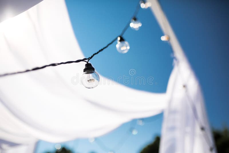 One long electric garland for lighting with white light bulbs against the background of a blue clear sky. Bokeh..Decorative royalty free stock image One long electric garland for lighting with white light bulbs against the background of a blue clear sky. Bokeh..Decorative royalty free stock image