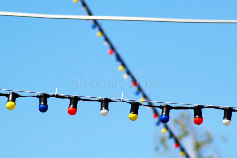 One long electric garland for lighting with white light bulbs against the background of a blue clear sky stock photo One long electric garland for lighting with white light bulbs against the background of a blue clear sky stock photo