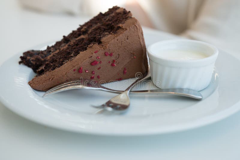 One piece of chocolate cake with two forks on white plate