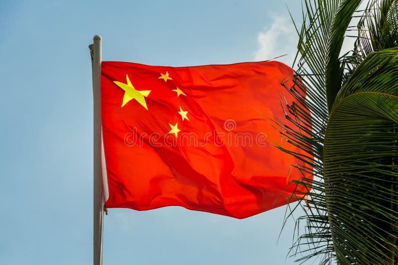One Rectangular Red Colored Flag with Yellow Stars is on a Blue Sky Background Stock Image