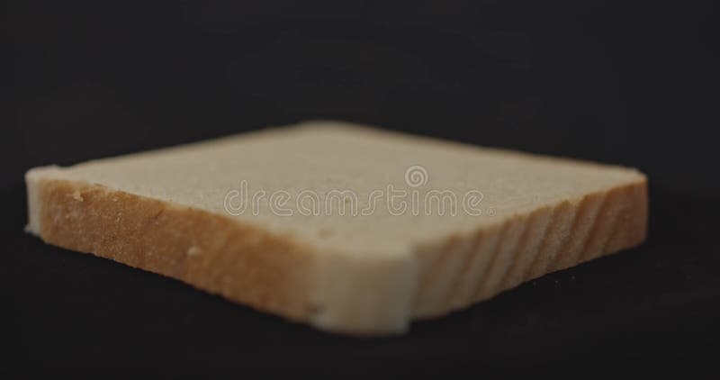One slice of fresh fragrant tasty toast wheat bread, close-up, on a black background. stock footage