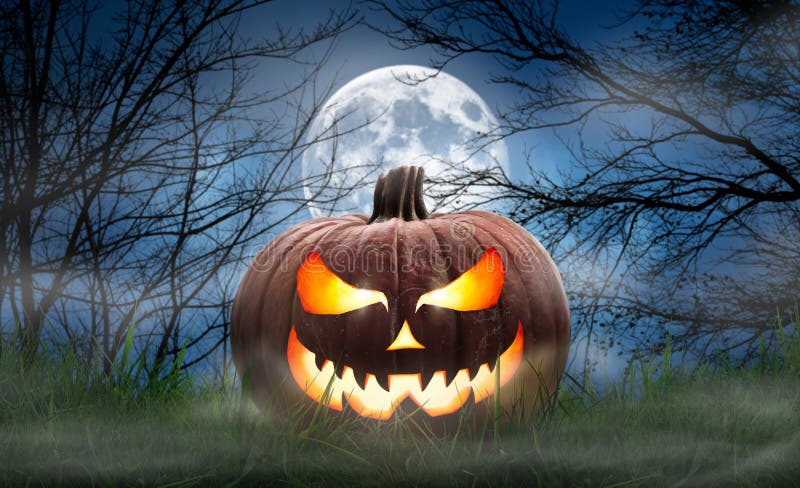 One spooky halloween pumpkin, Jack O Lantern, with an evil face and eyes on the grass with a misty night sky background with a full moon