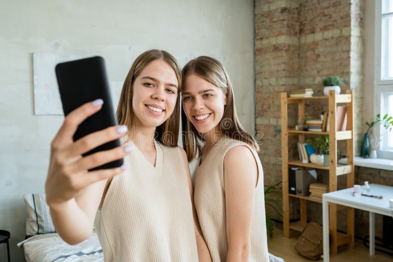 One of Twin Girls with Smartphone Making Selfie with Her Sister Stock ...