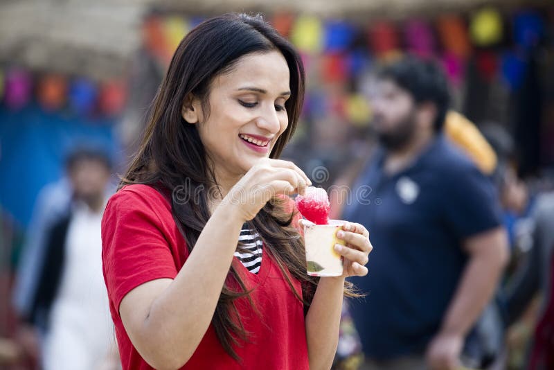 One women eating flavored ice gola dipped in syrup. 