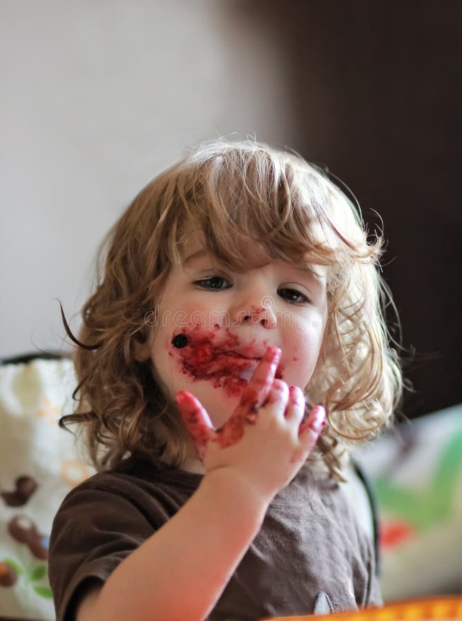 One year old baby girl eating delicious blueberry and black currant pie with her face dirty