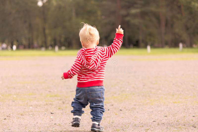 One year toddler running in the autumn park. Back view stock image