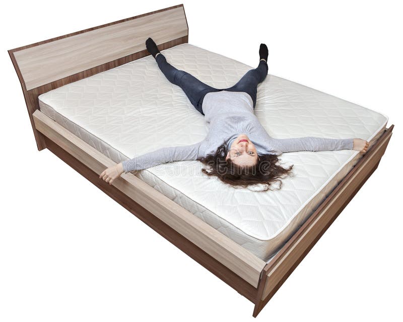 One young Caucasian woman relaxing on a spring mattress, huge wooden bed is...