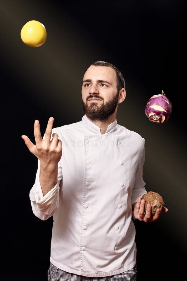One young man, chief uniform, throwing food, studio photoshoot, having fun. royalty free stock photo One young man, chief uniform, throwing food, studio photoshoot, having fun. royalty free stock photo