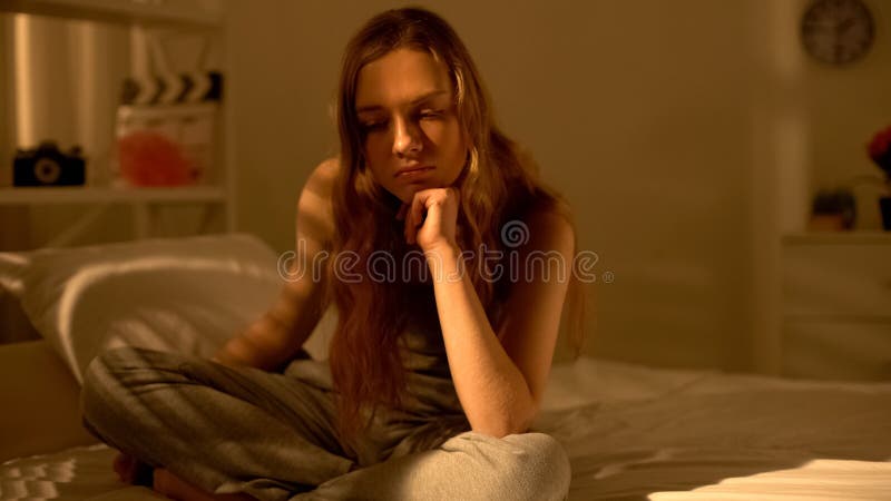 Ongelukkige tiener die over het bed van de probleemzitting, denken die aan eenzaamheid lijden royalty-vrije stock afbeelding Ongelukkige tiener die over het bed van de probleemzitting, denken die aan eenzaamheid lijden royalty-vrije stock afbeelding