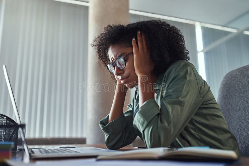 Ongerust gemaakte jonge Afrikaanse onderneemster op het haar werk stock afbeeldingen Ongerust gemaakte jonge Afrikaanse onderneemster op het haar werk stock afbeeldingen