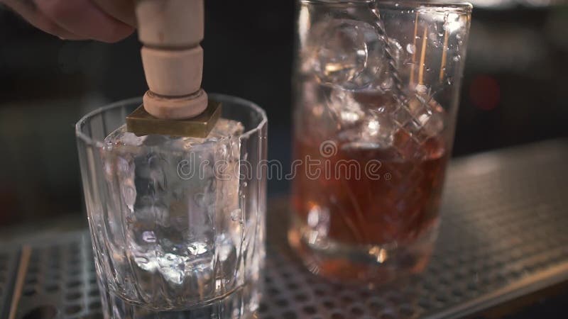 Onherkenbare barman die ijs voor coctails met icebreaker in glas voor alcoholschoten prikken in moderne bar Sluit omhoog