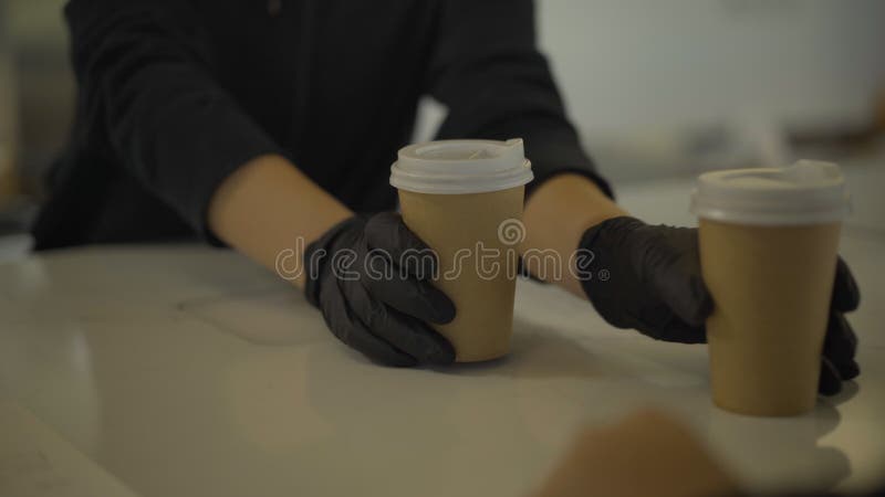 Onherkenbare barman in zwarte handschoenen die twee koffiekopjes doorgeven aan de kaukasus over de toonbank. barista-serverclient