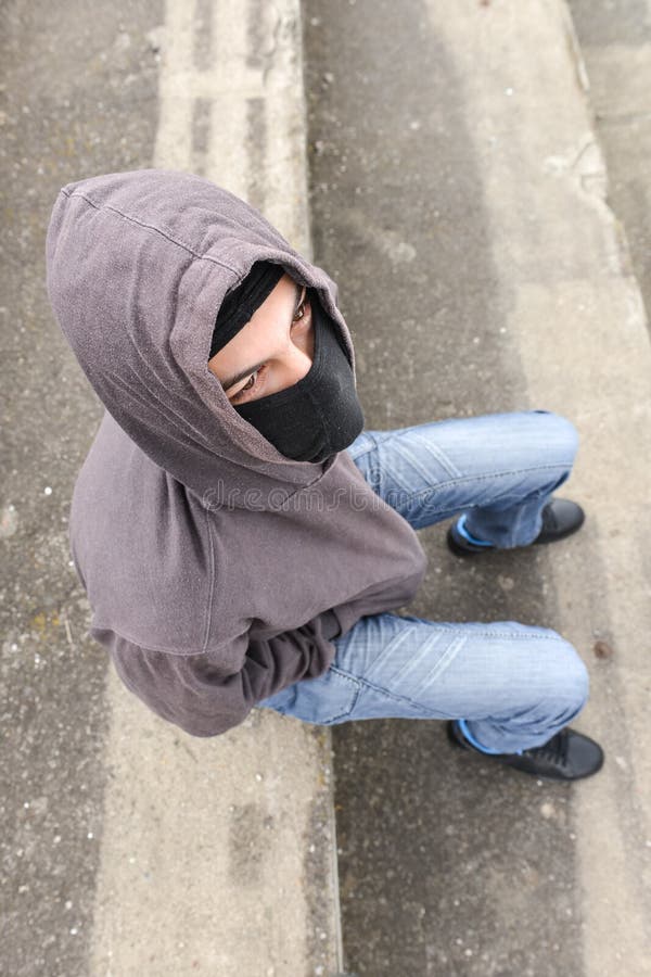 Onherkenbare jonge mens die zwarte balaclava zitting op oud dragen royalty-vrije stock foto's Onherkenbare jonge mens die zwarte balaclava zitting op oud dragen royalty-vrije stock foto's