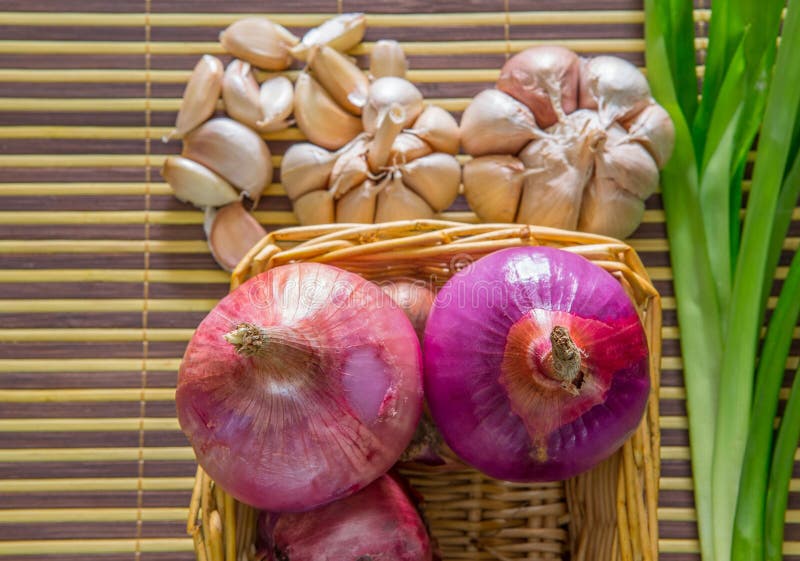 Onion, garlic and pandan leaves on a bamboo mat. Onion, garlic and pandan leaves on a bamboo mat.