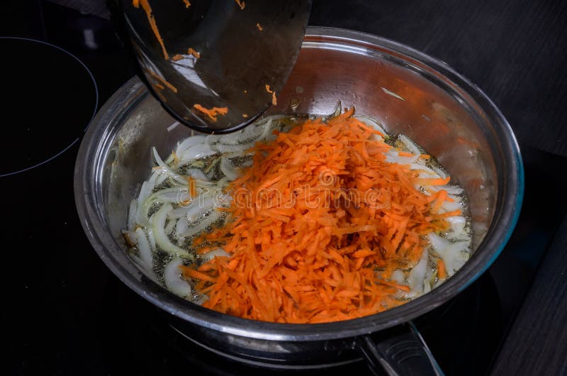 Onions and Carrots are Fried in a Pan in Sunflower Oil Stock Photo