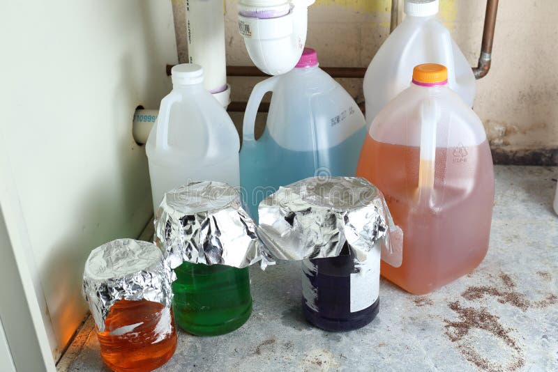 Variety in mysterious chemicals stored improperly and unlabeled in jugs and jars under a sink. Variety in mysterious chemicals stored improperly and unlabeled in jugs and jars under a sink