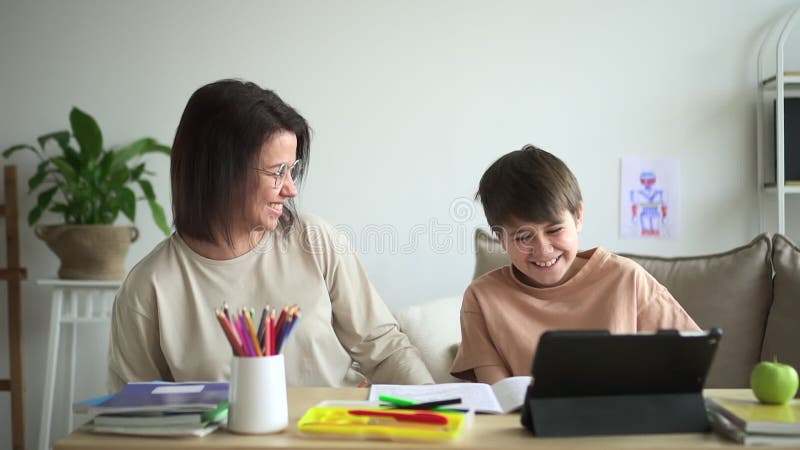 Online-avstånd : Mamma son som har kul och sitter vid bordet under utbildning i hemmet.. arkivfilmer
