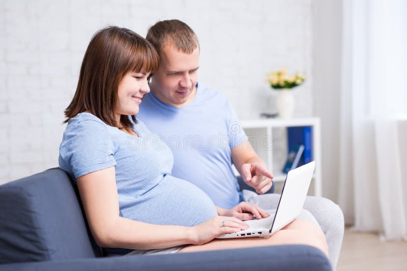 Online het winkelen concept - zwangere vrouw en haar echtgenoot die l gebruiken stock fotografie Online het winkelen concept - zwangere vrouw en haar echtgenoot die l gebruiken stock fotografie