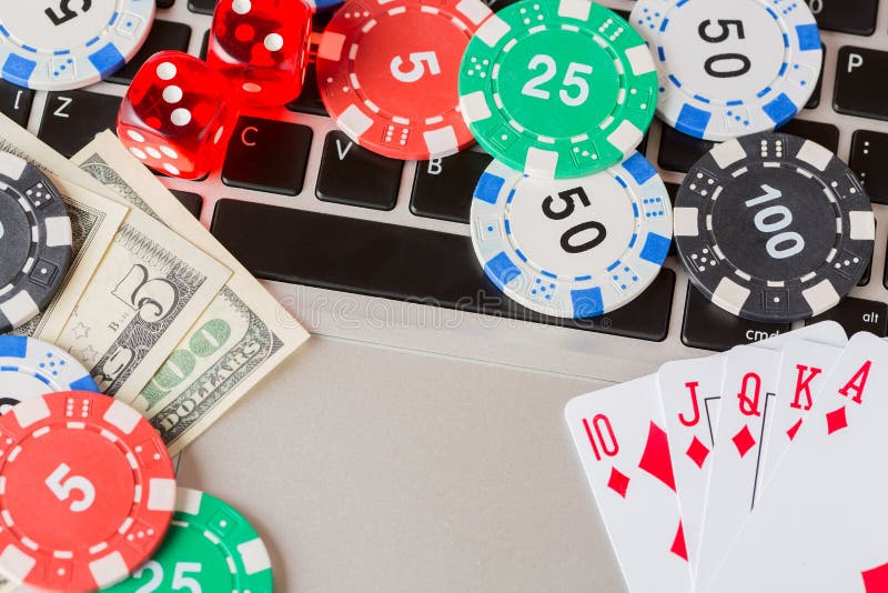 Online poker casino theme. Gambling chips with dice, playing cards, american dollars on laptop.