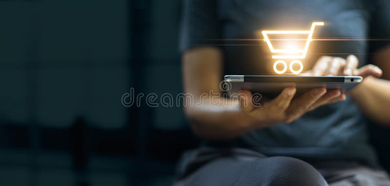 Online shopping and digital marketing concept, Woman using digital tablet with shopping cart icon on screen on dark background stock image