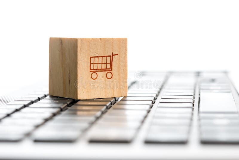 Shopping Online e di e-commerce concetto con un blocco di legno con un'icona di un carrello della spesa in piedi su una tastiera di un computer, visto angolo basso con copyspace.
