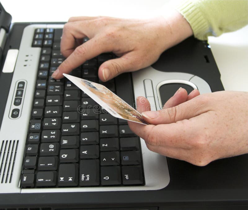 Una mujer escribiendo en crédito tarjeta sobre el computadora portátil.