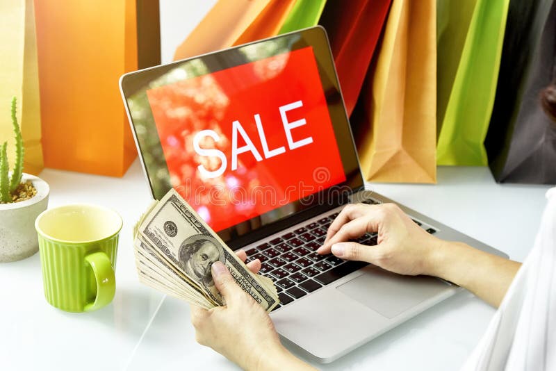 Online shopping, Shopaholic woman holding money cash, Sale promotion sign on laptop computer.